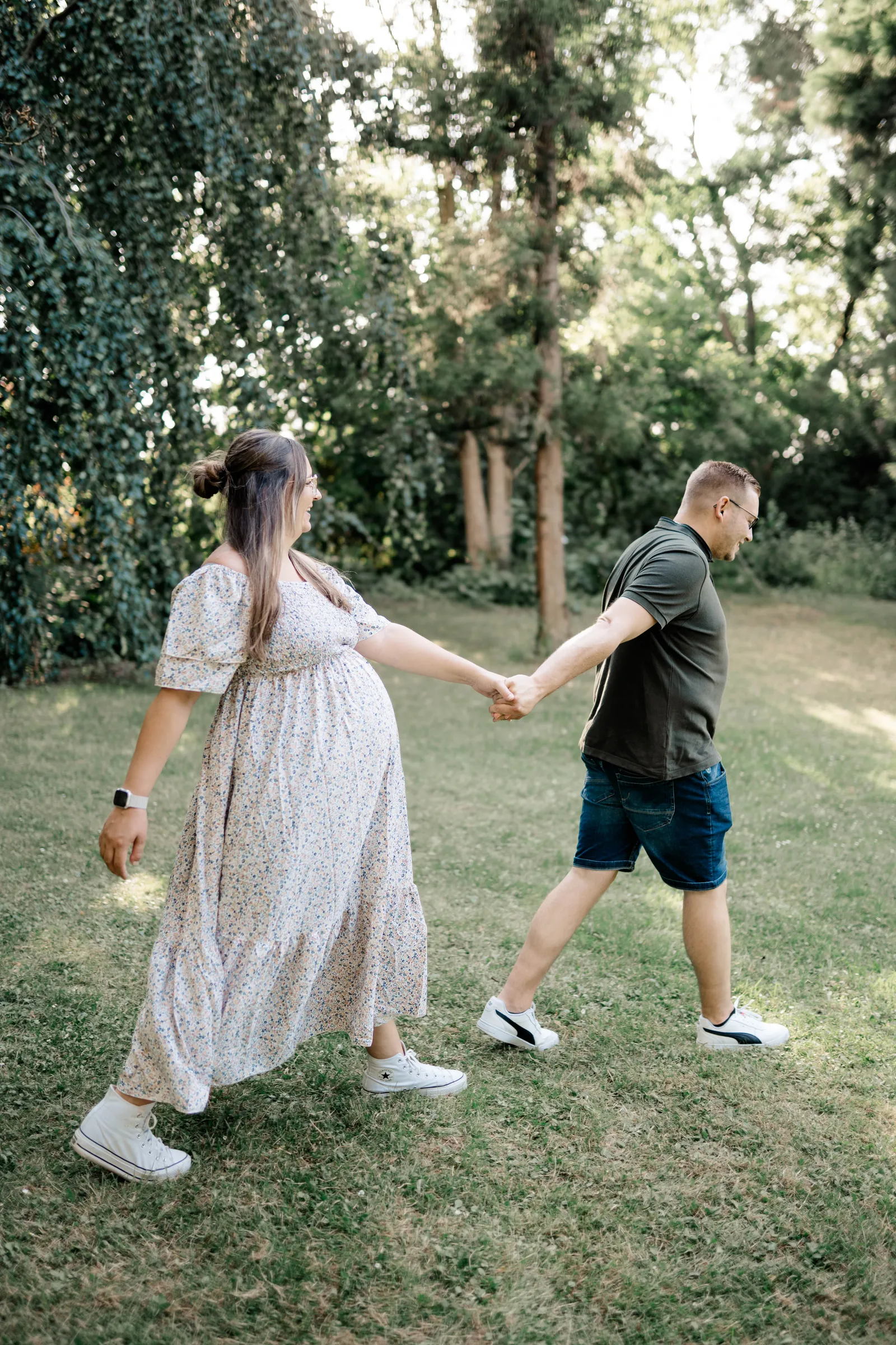 Paar mit Babybauch beim Spazieren, Hand in Hand