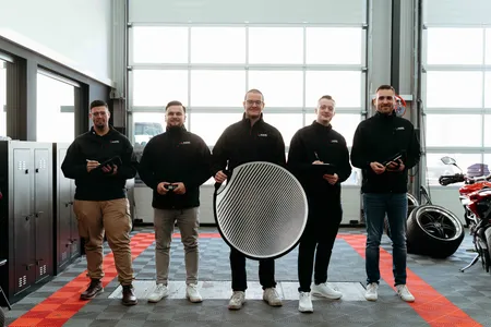 Team eines Autohauses mit Reflektor in der Werkstatt